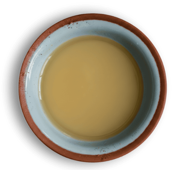Sandalwood oil in a small clay bowl, top view, with a clean white background